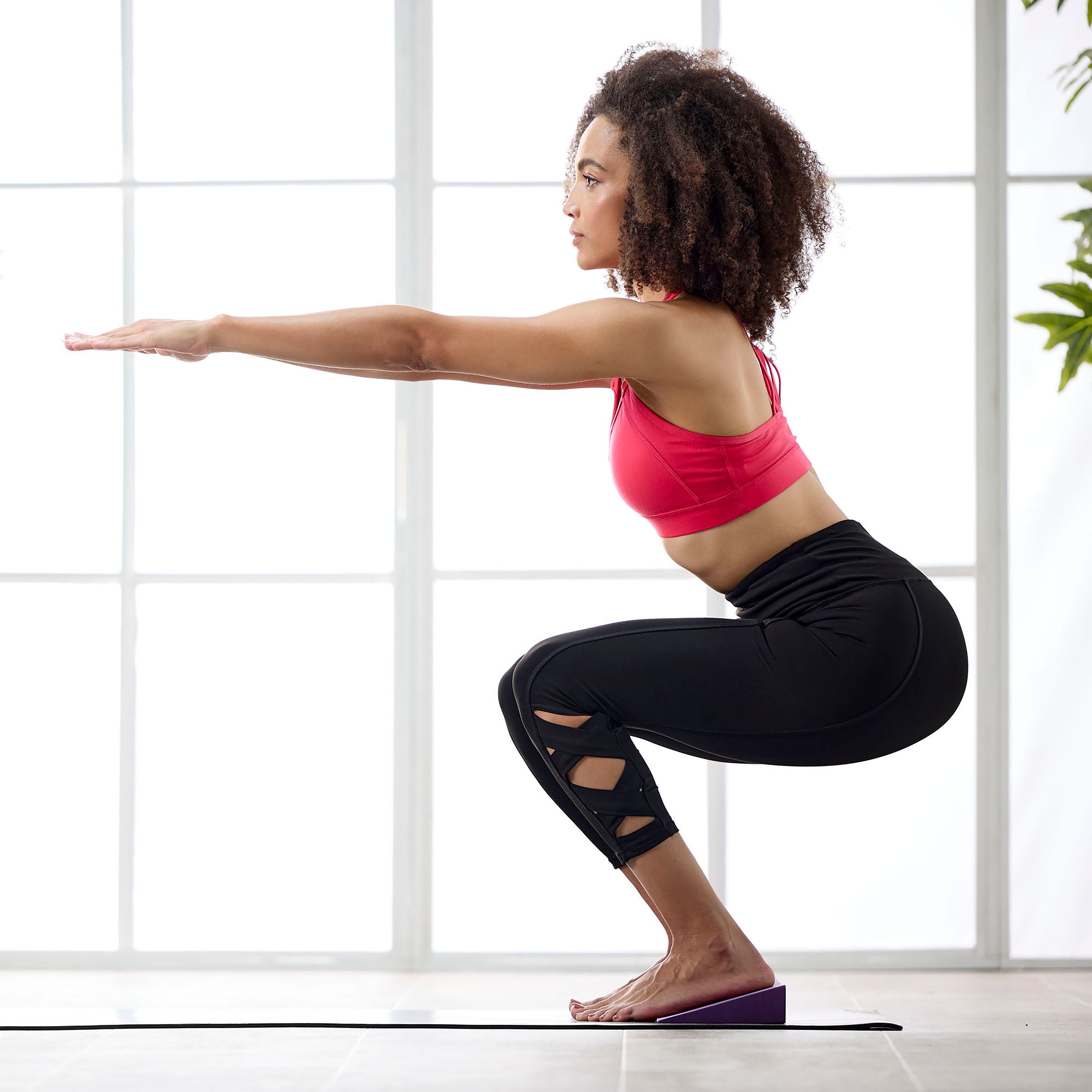 Person in modified chair pose with feet on Yoga Wedge